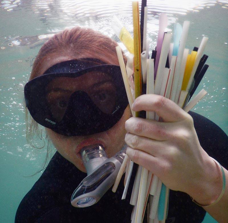 Diver with single-use plastic straws in ocean 