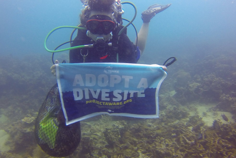 Nic Emery diving with Adopt a Dive Site banner