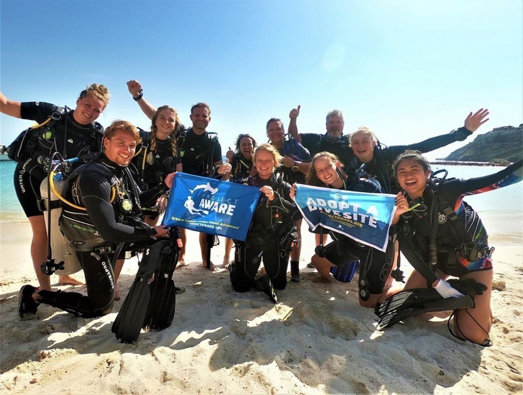 image of divers on the beach with Project AWARE flag